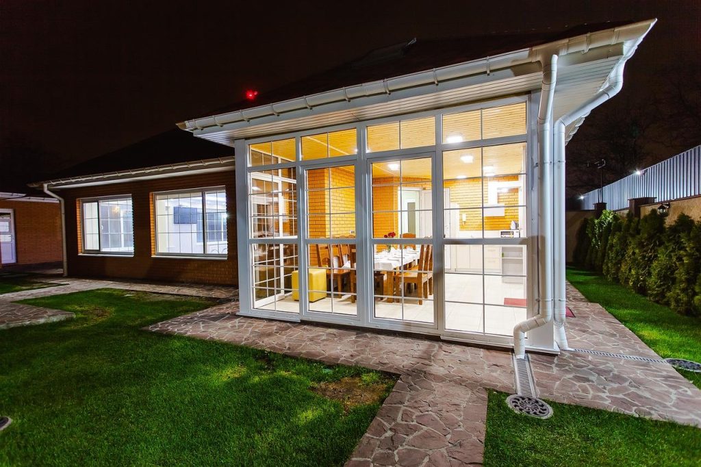 Moderne glazen schuifwand veranda aan een woning, toont transparante wanden en flexibele buitenleefruimte met natuuruitzicht